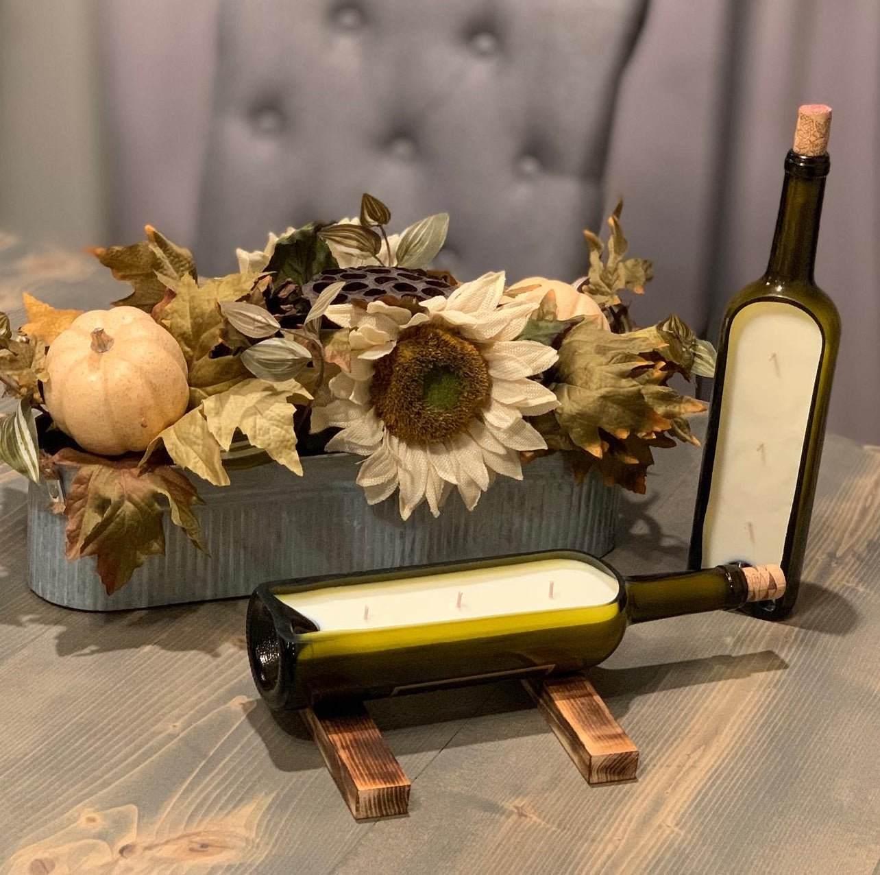 Long Cut Candle in repurposed liquor bottles with three wicks and hand-carved barnwood stands beside autumn floral centerpiece