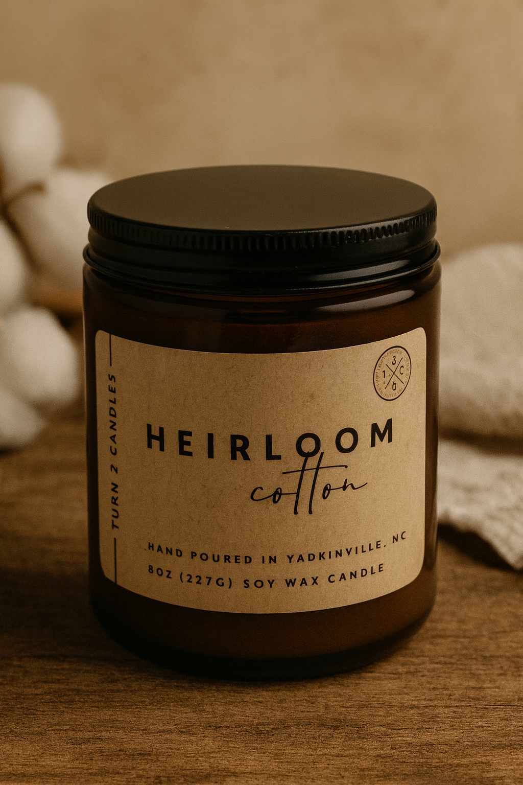 Candle jar labeled 'Heirloom Cotton' on a wooden surface with a blurred background